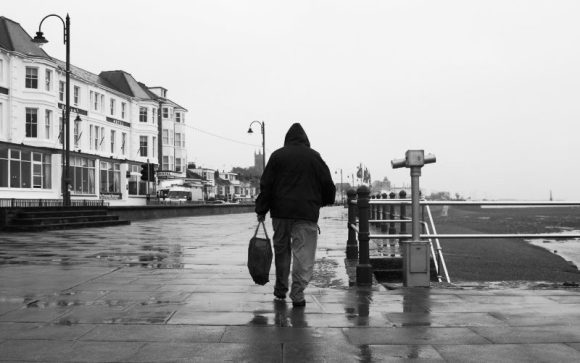 An anorak-wearing walker on the prom.