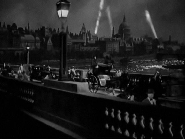 A vista of London with Waterloo Bridge in the foreground, bustling with people.