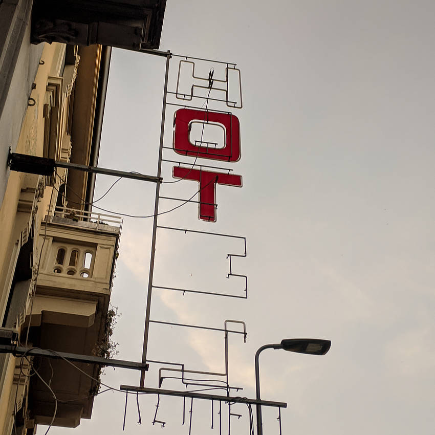 A broken neon sign that once read HOTEL but now has only two letters, O and T, remaining.