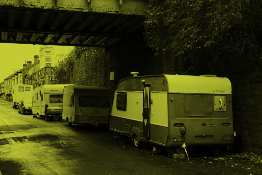Caravans parked beneath a railway bridge.