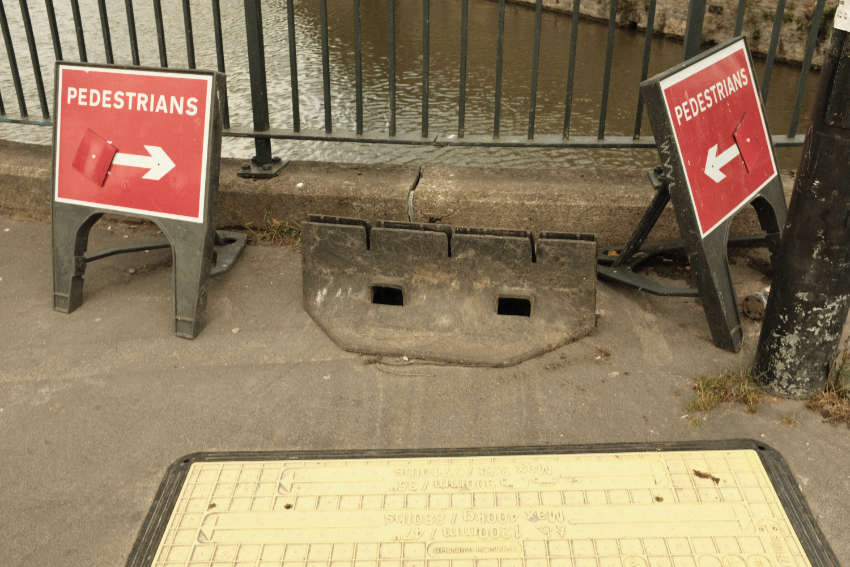 Two temporary signs point at each other, directing pedestrians to a standstill in between.