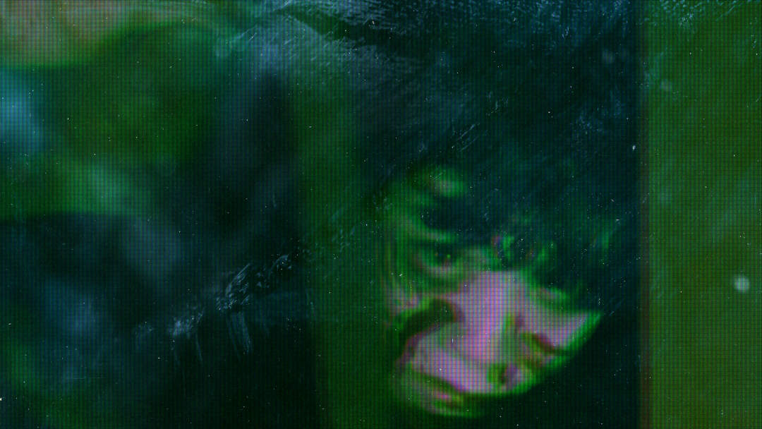 A heavily edited film still: a female ghost stares intensely through grain and screen artefacts.