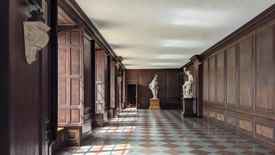 A gallery at Hampton Court Palace with chequered floor and wood panelling.
