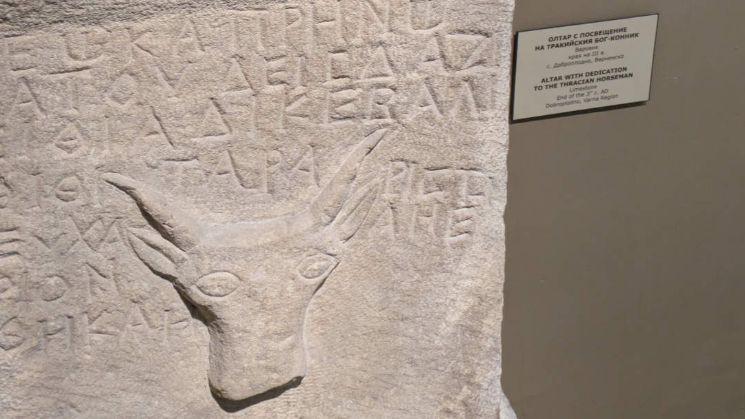 A fairly crude stone carving of the head of a horse surrounded by what I think is ancient Greek. An interpretation card next to it says "Altar with dedication to the Thracian Horseman".
