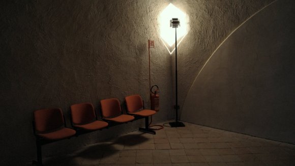 Four seats against a concrete wall in a dark corner of an institutional building.