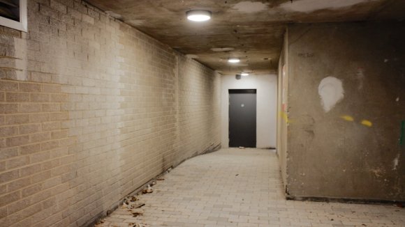A doorway at the end of a concrete hallway.