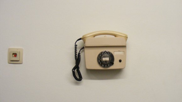 An old beige institutional telephone on a white wall.