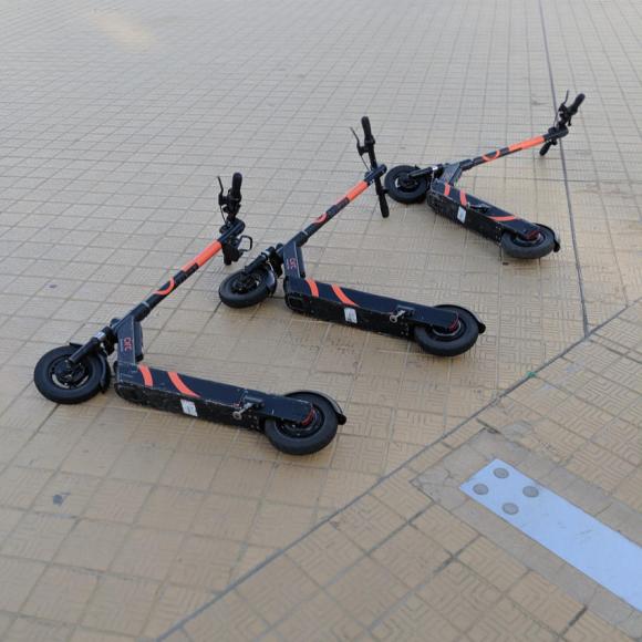 E-scooters scattered on a pavement.