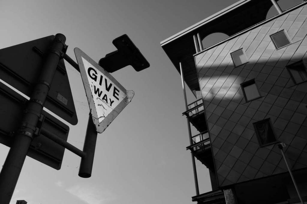 A hot city street with sunlight blasting a block of flats and shining from a street sign.