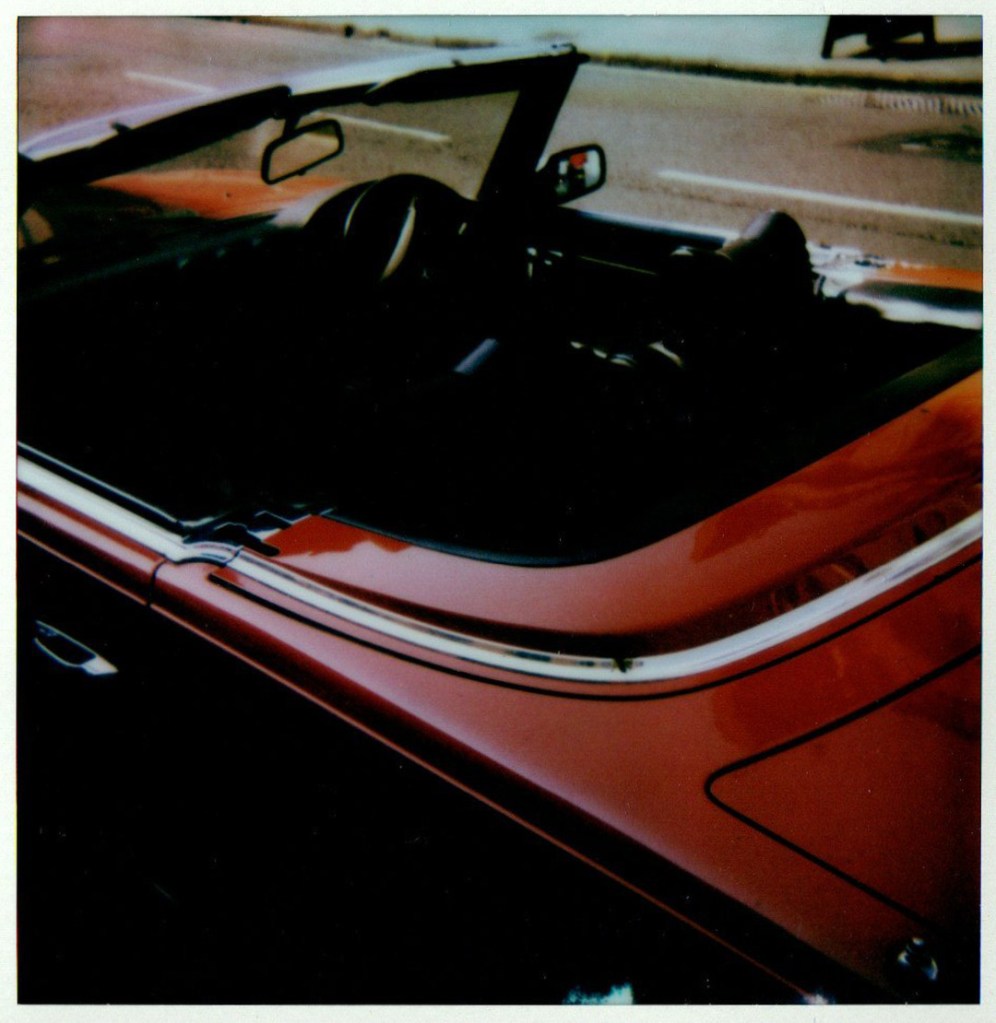 A red sports car with its top open.